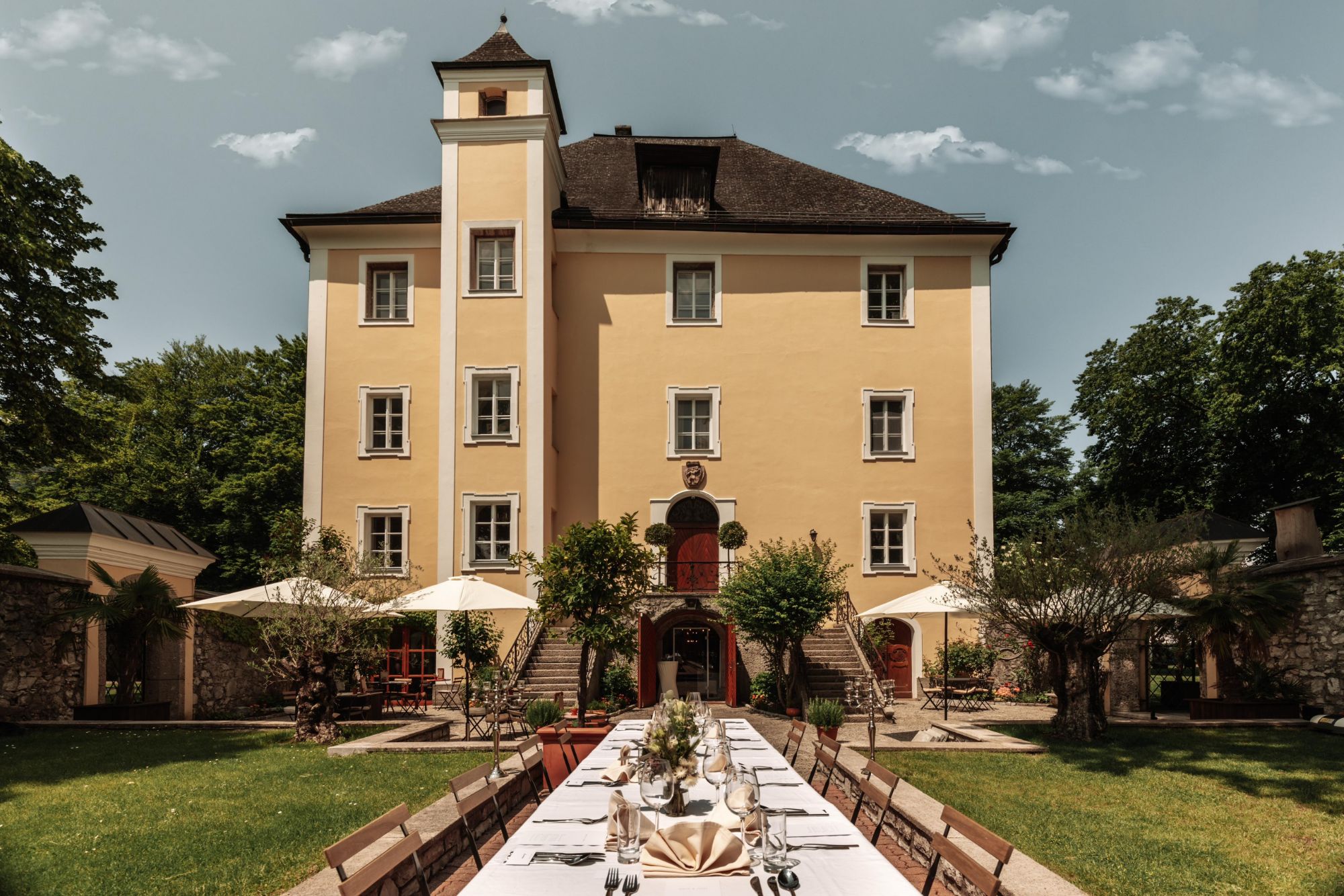 Schloss Wiespach in Hallein — gelbe Barockfassade mit festlich gedeckter Tafel im Garten.